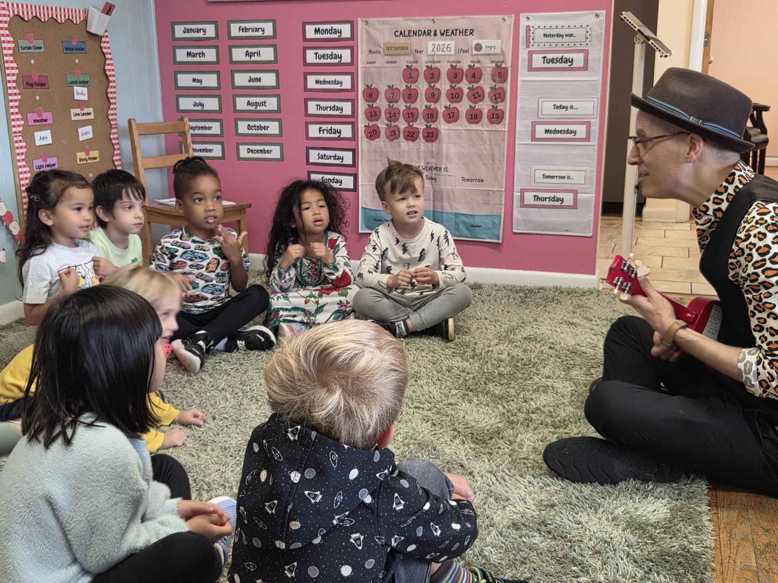 Preschoolers singing along with a visiting musician playing a ukulele