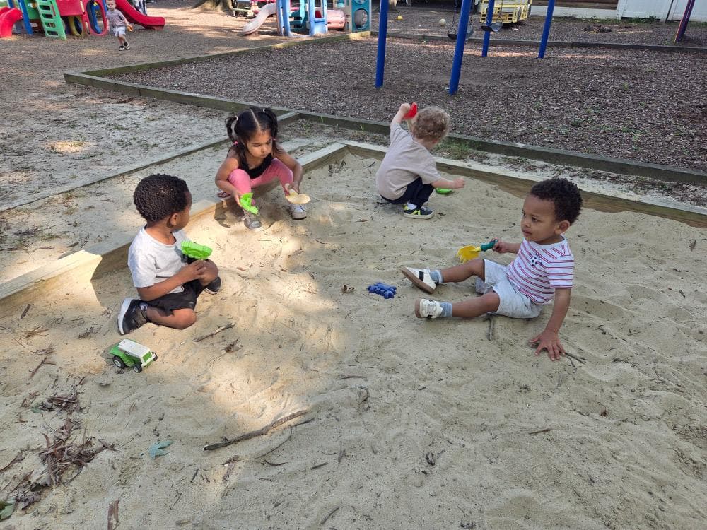 Toddlers digging with shovels in the playground sandbox