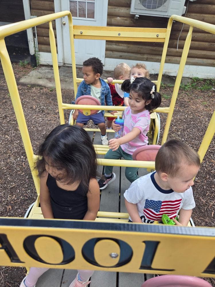 Toddlers climbing on the yellow school-bus play structure