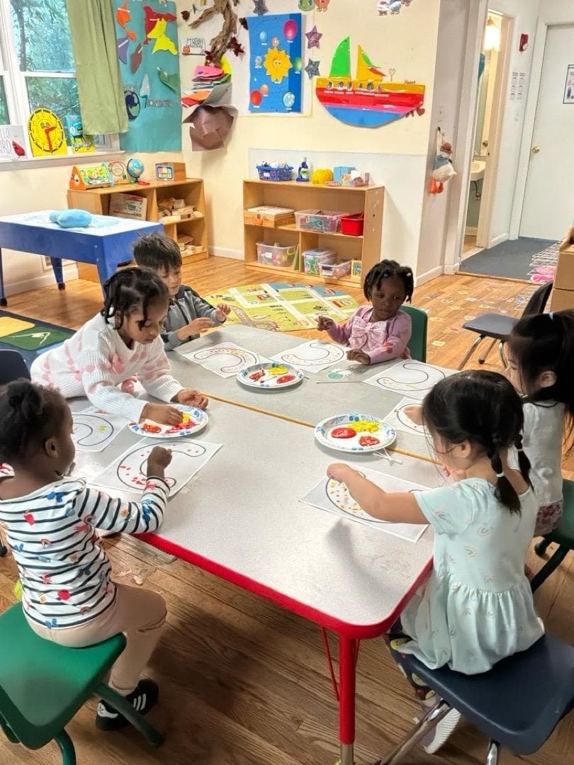 Children at a classroom table decorating letter shapes